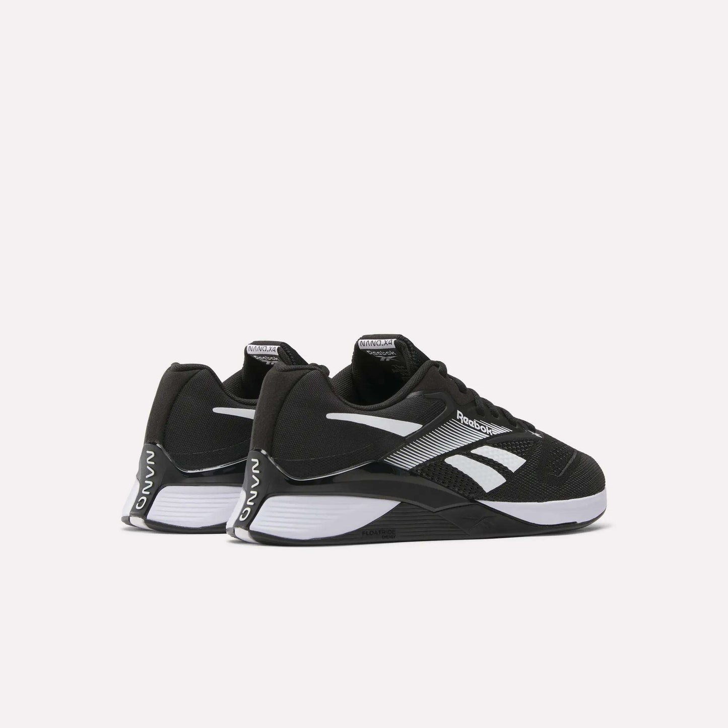 A pair of Reebok Nano X4 Training Shoes with black Flexweave uppers, white soles, and logo accents are positioned side by side at an angle on a plain white background.