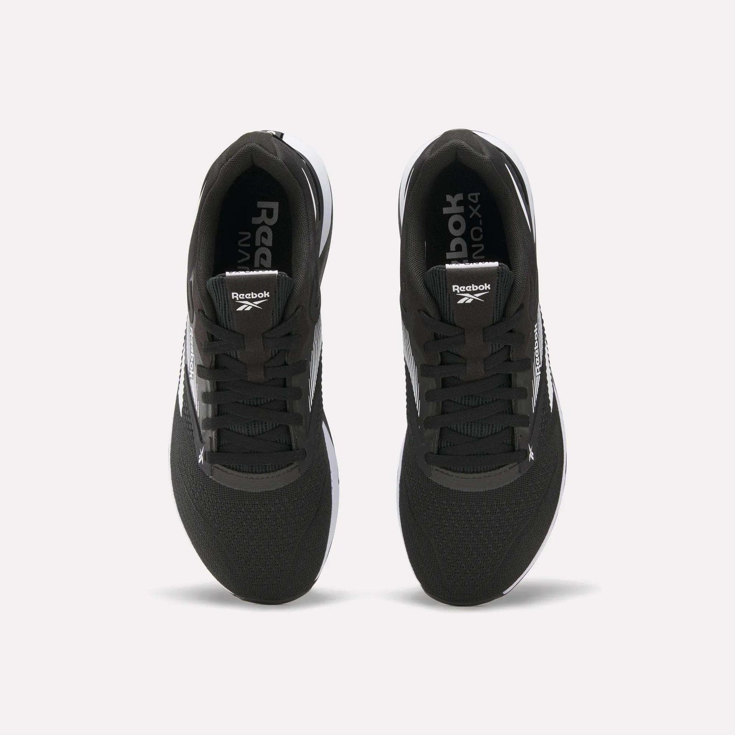 Top view of a pair of black Reebok Nano X4 Training Shoes with white soles and visible Reebok logos on the tongue and inner sole, displayed side by side on a white background.