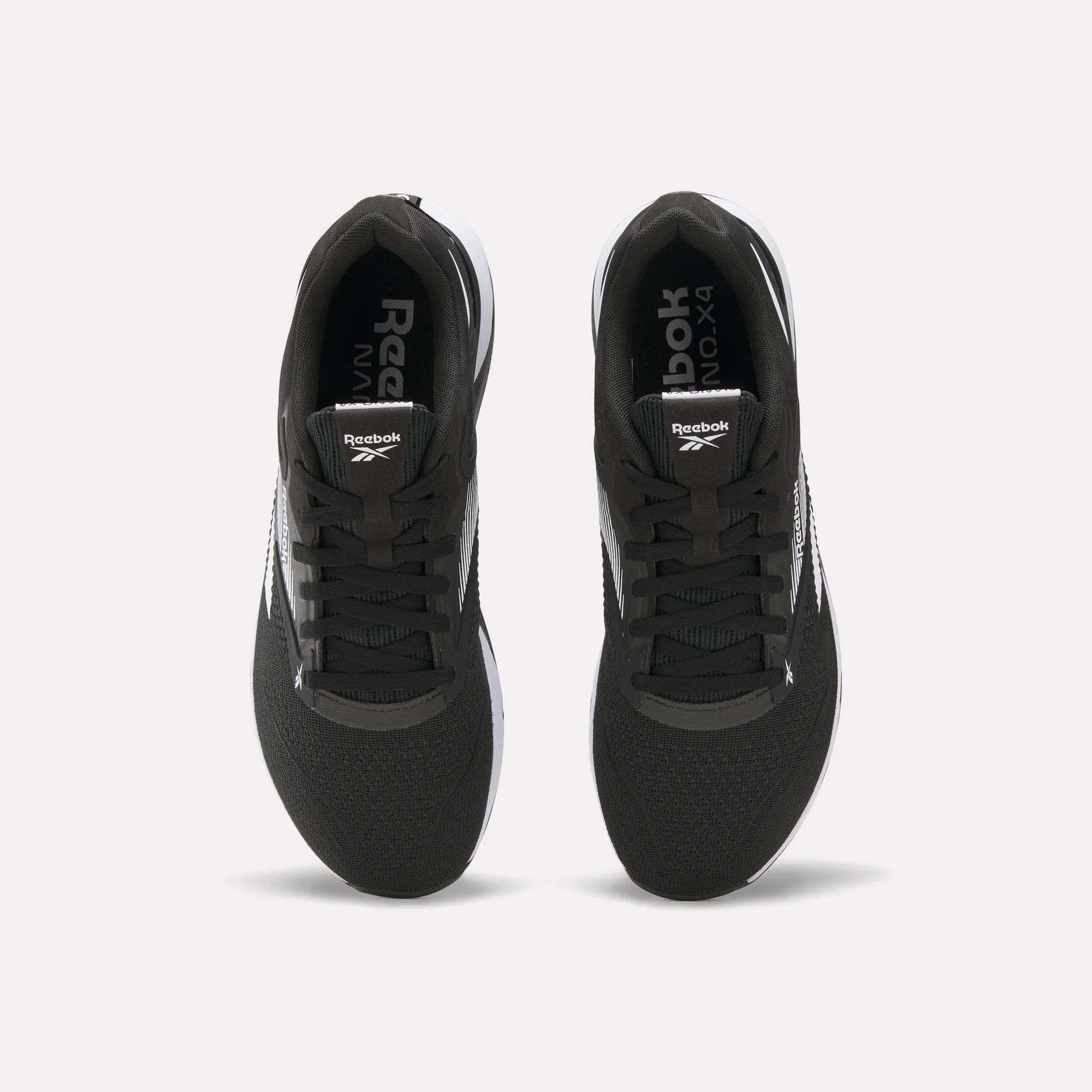 Top view of a pair of black Reebok Nano X4 Training Shoes with white soles and visible Reebok logos on the tongue and inner sole, displayed side by side on a white background.
