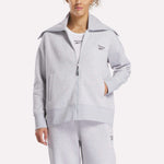 A woman wearing a grey Reebok Women's Wardrobe Essentials Retro Zip Top and soft fleece sweatpants.