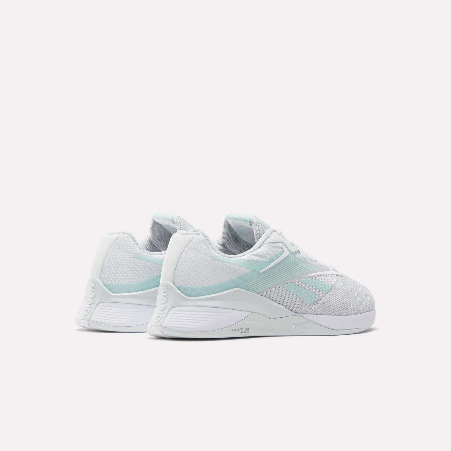 A pair of Reebok Women's Nano X4 Training Shoes in white and pale mint green with Floatride Energy Foam are shown side by side on a light background, displaying their sides and backs.