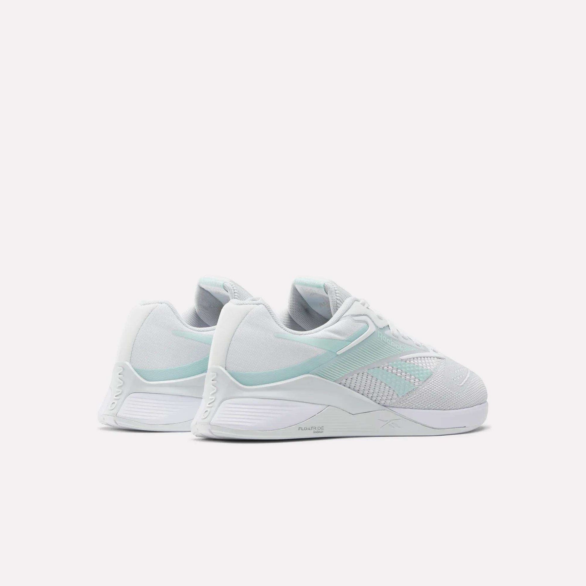 A pair of Reebok Women's Nano X4 Training Shoes in white and pale mint green with Floatride Energy Foam are shown side by side on a light background, displaying their sides and backs.