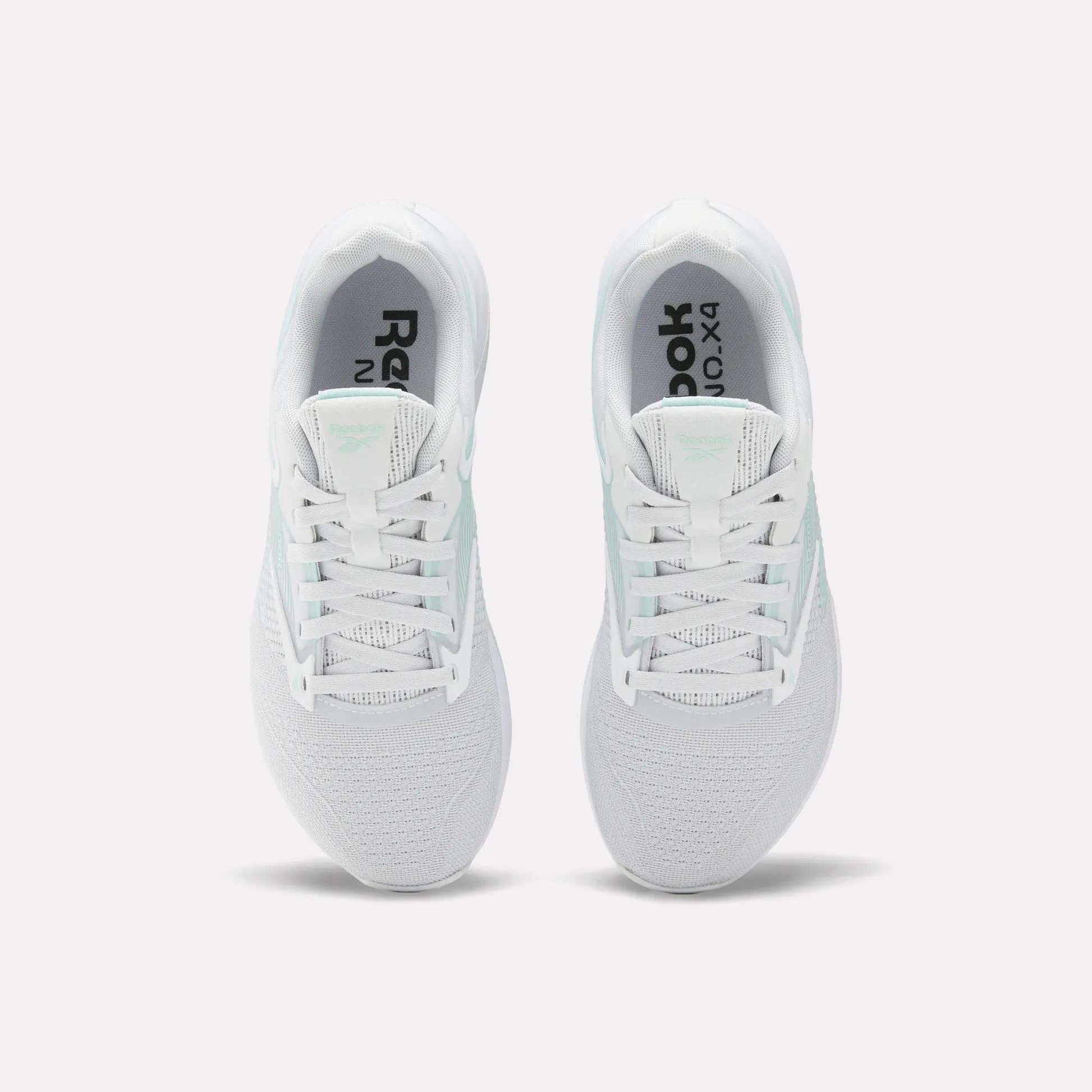 A pair of white Reebok Women's Nano X4 Training Shoes seen from above, featuring breathable mesh uppers, laces, black Reebok branding on the insoles, and Floatride Energy Foam cushioning for comfort.