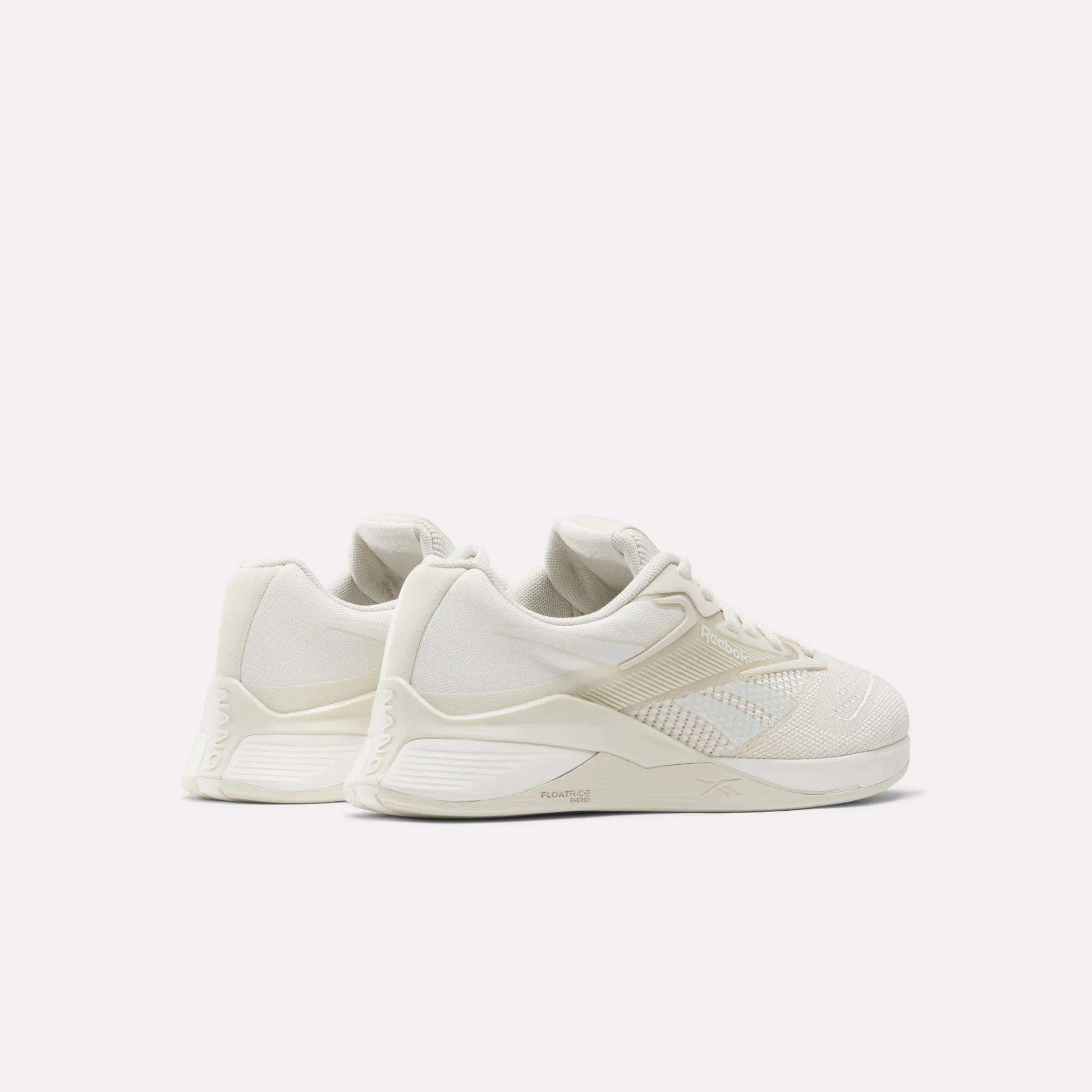 The Women's Nano X4 Training Shoes by Reebok are off-white with textured details, a Flexweave upper, low-top design, and chunky soles, displayed against a plain white background.