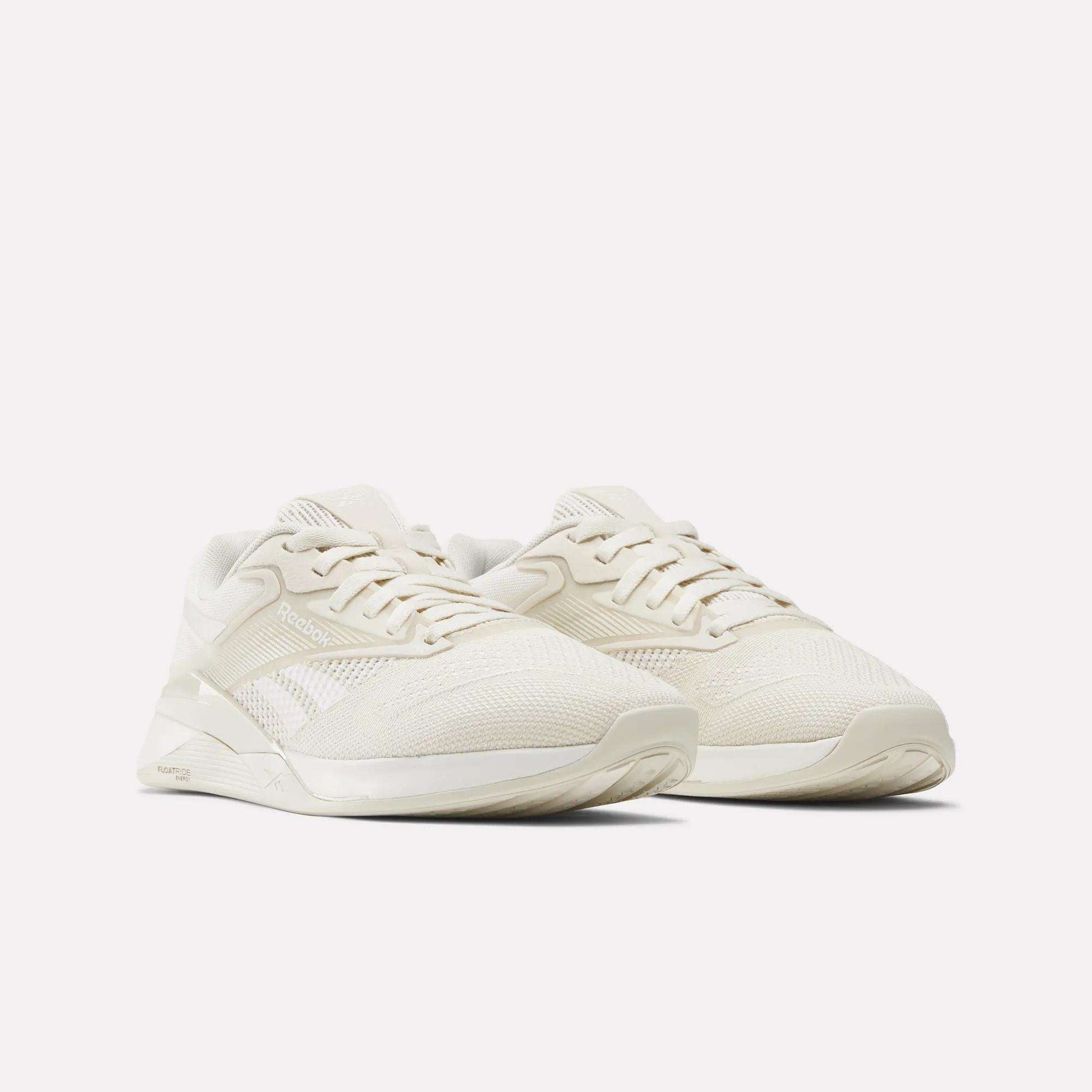 A pair of Women's Nano X4 Training Shoes by Reebok, in off-white with mesh and synthetic Flexweave uppers, laced and placed side by side on a plain white background.