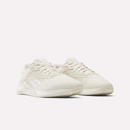 A pair of Women's Nano X4 Training Shoes by Reebok, in off-white with mesh and synthetic Flexweave uppers, laced and placed side by side on a plain white background.