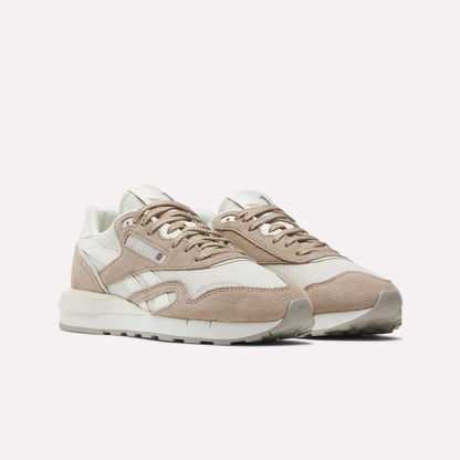 The Reebok Women's Classic Nylon 89 Shoes feature beige and white suede and mesh uppers, white midsoles, beige outsoles, and white laces for a retro look, shown against a plain white background.