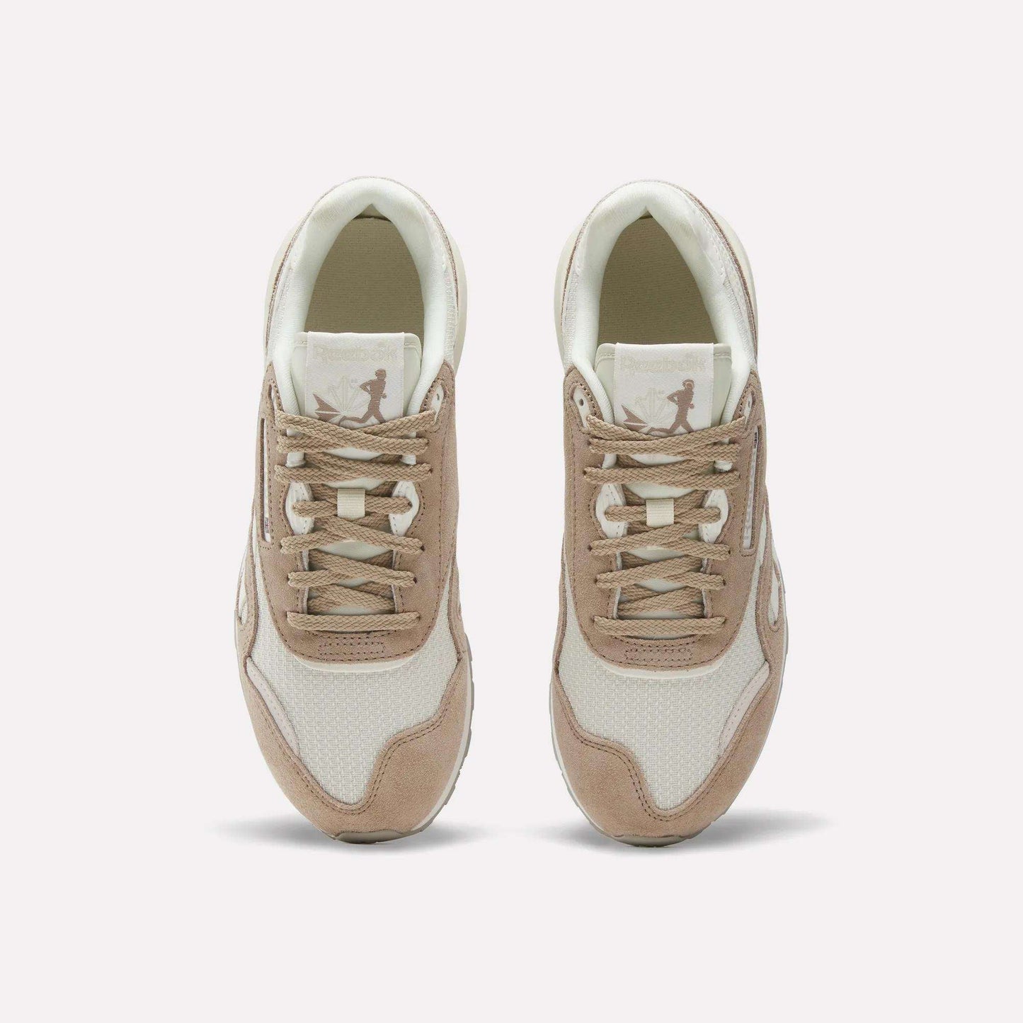 A pair of Women’s Classic Nylon 89 Shoes by Reebok in beige and white, seen from above, display laces, mesh texture, suede overlays, and a retro look with the Reebok logo on each tongue.
