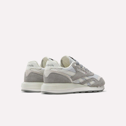 The Reebok Women's Classic Nylon 89 Shoes, shown in grey and white suede and mesh with retro styling, feature the Reebok logo on the heel and side, displayed from back and side angles.