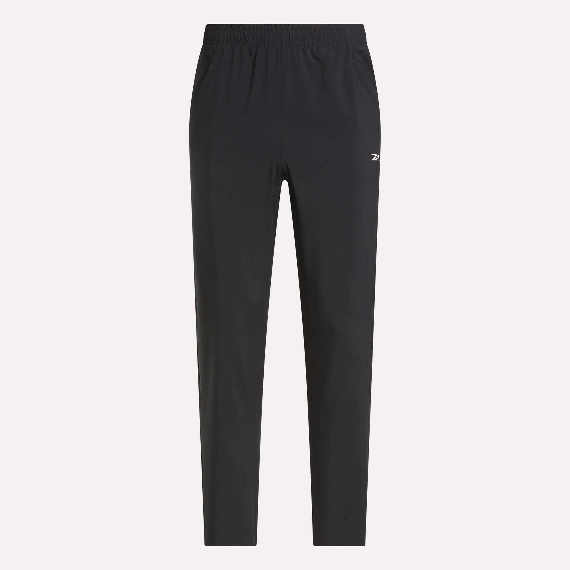 Reebok Men's Woven Pants with elastic waistband and side pockets, featuring a small white logo on the left thigh. Lightweight polyester in black, shown on a light plain background for a sleek, sporty style.