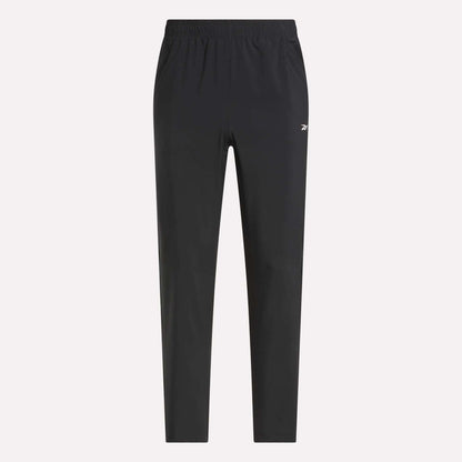 Reebok Men's Woven Pants with elastic waistband and side pockets, featuring a small white logo on the left thigh. Lightweight polyester in black, shown on a light plain background for a sleek, sporty style.