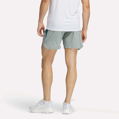 A man wearing Reebok Men's Run Shorts with inner tights and a white tank top.
