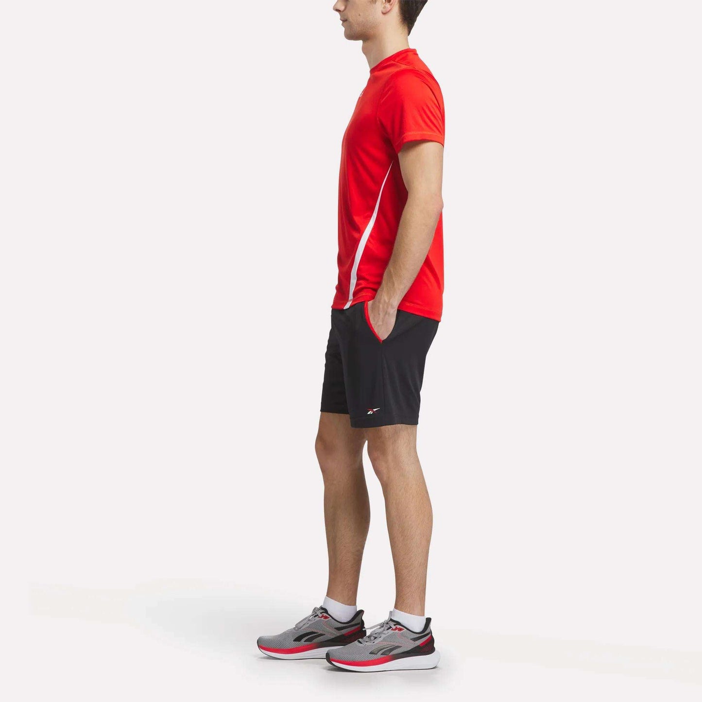 A man wearing a Reebok Men's Train Blocked T-Shirt and black shorts.