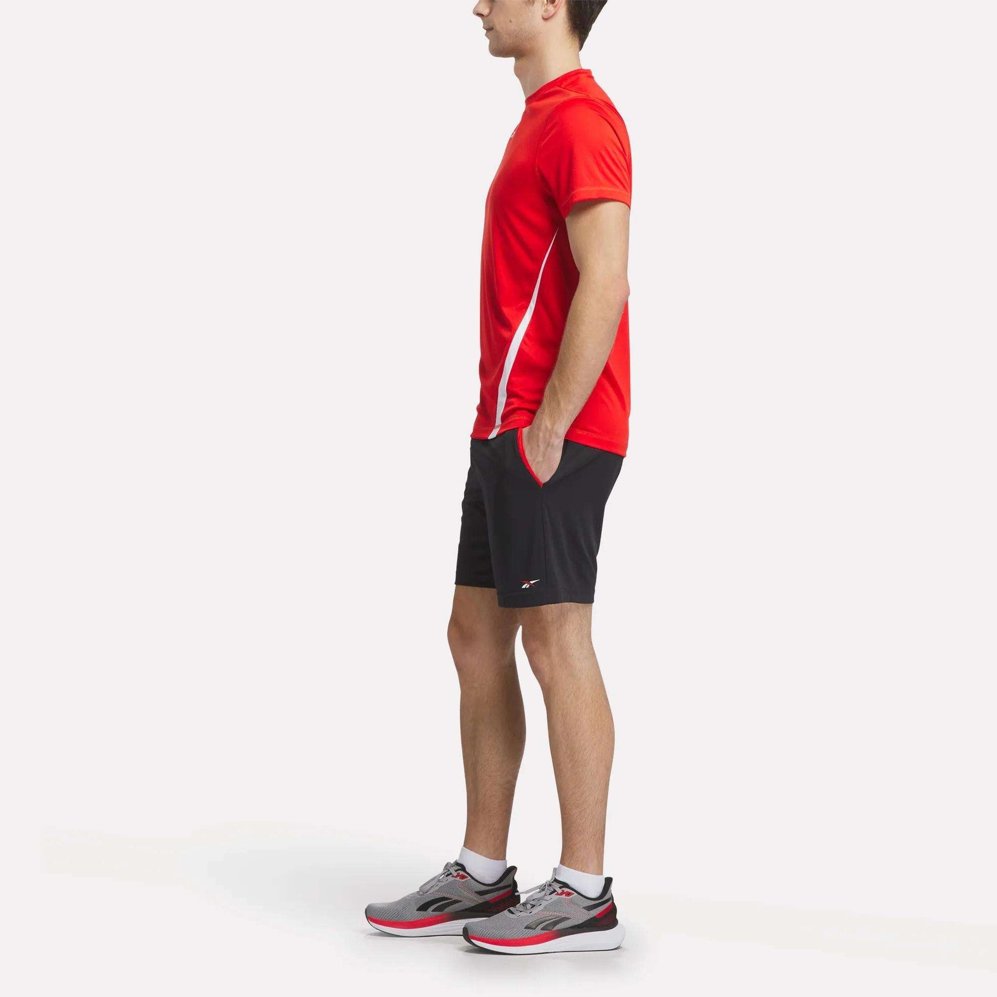 A man wearing a Reebok Men's Train Blocked T-Shirt and black shorts.