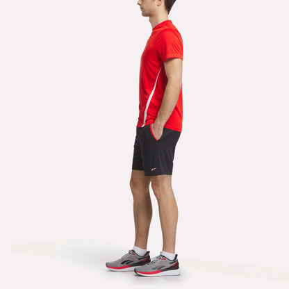 A man wearing a Reebok Men's Train Blocked T-Shirt and black shorts.