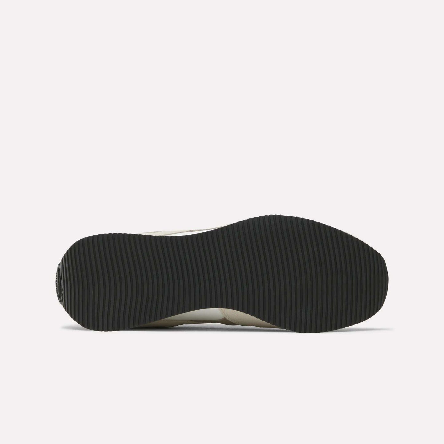 The image shows the black, ribbed outsole of Reebok R100 Shoes viewed from below on a white background, evoking classic '70s running style.
