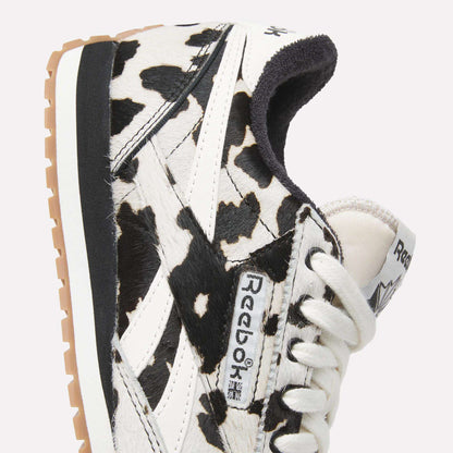 Close-up of Reebok Women's Classic AZ Shoes with a striking black and white animal print, white laces, beige sole, and prominent Reebok logo on the side and tongue.