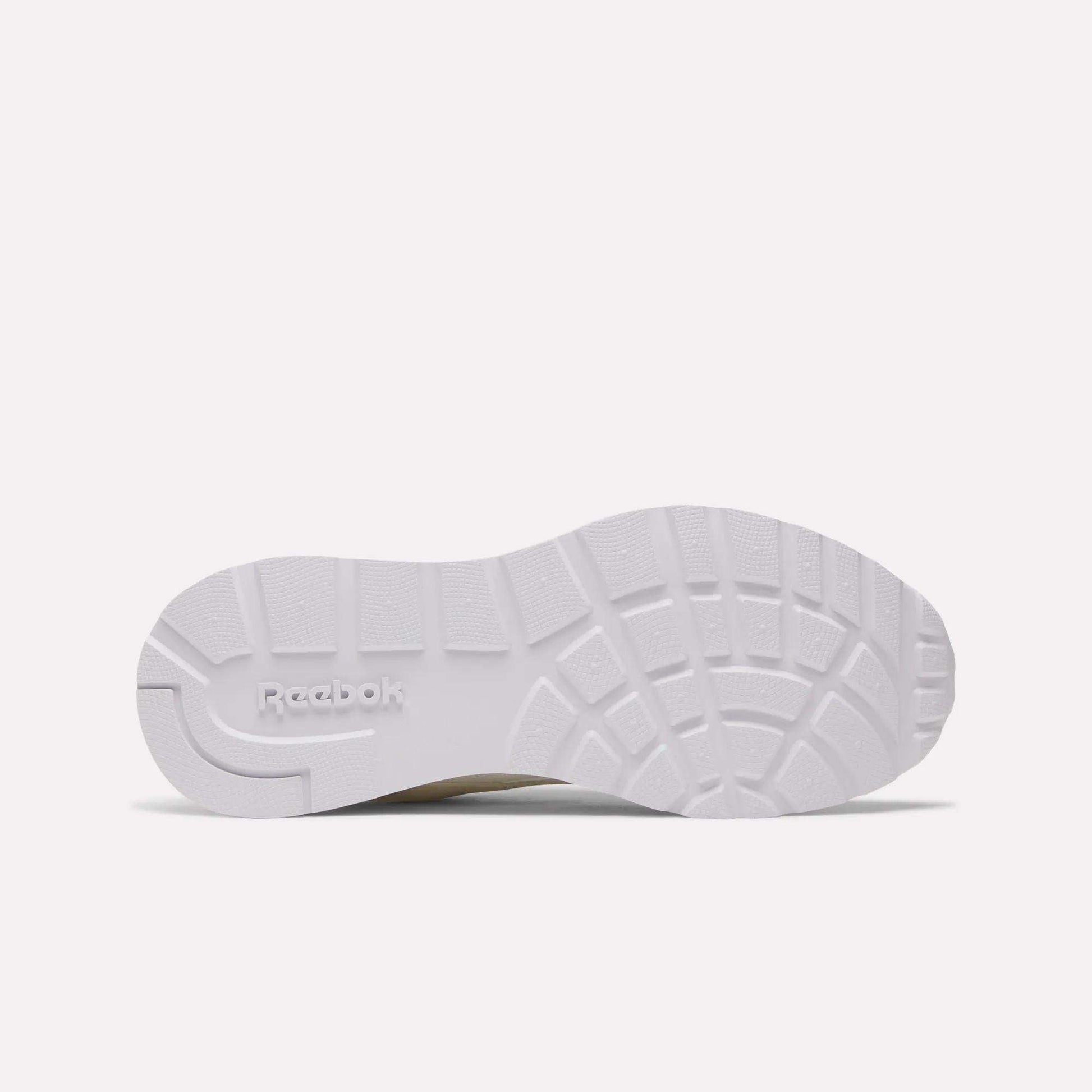 The image displays the white, textured sole of the Reebok Women's GL1100 Shoes viewed from below, showing the tread pattern and embossed Reebok logo—ideal for comfortable, everyday wear.