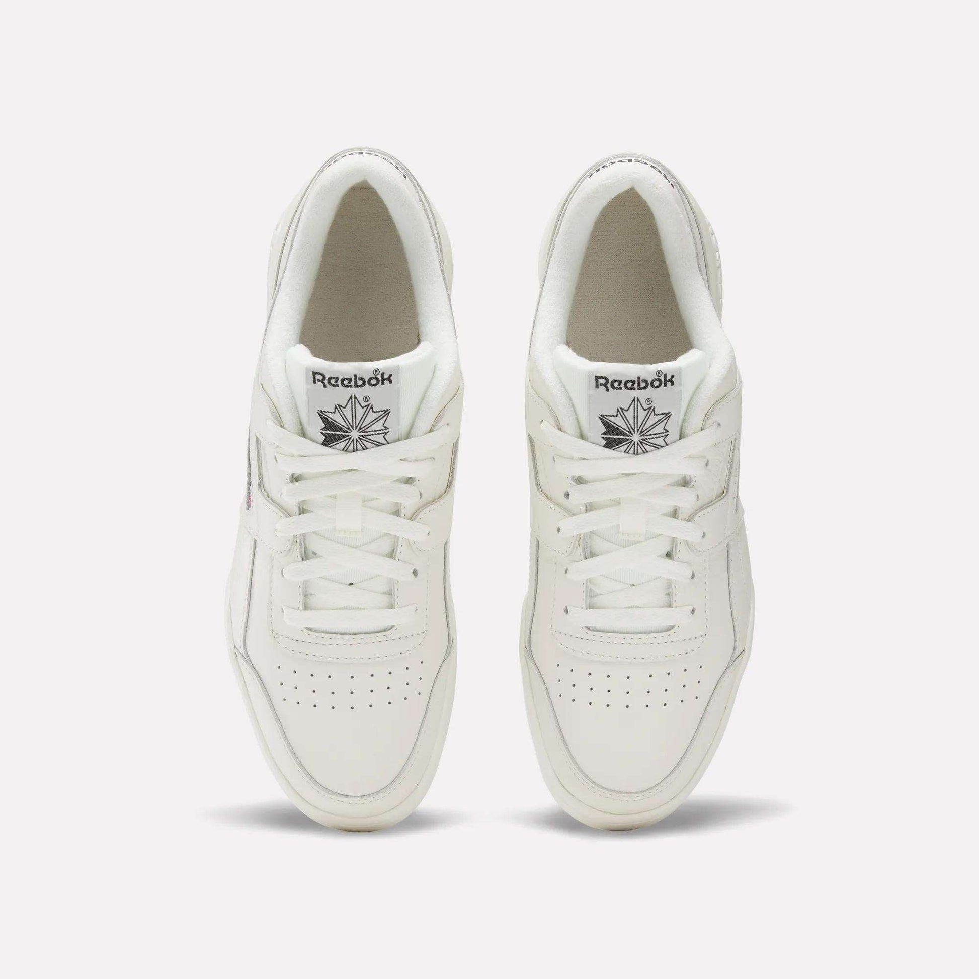A pair of white Reebok Workout Plus Shoes viewed from above showcases classic '80s fitness style. The tops, laces, and Reebok logo on each tongue are visible, set against a plain light background.