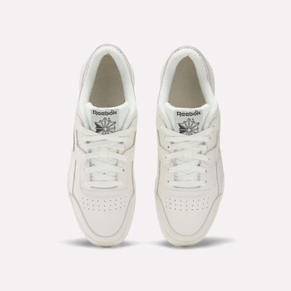 A pair of white Reebok Workout Plus Shoes viewed from above showcases classic '80s fitness style. The tops, laces, and Reebok logo on each tongue are visible, set against a plain light background.