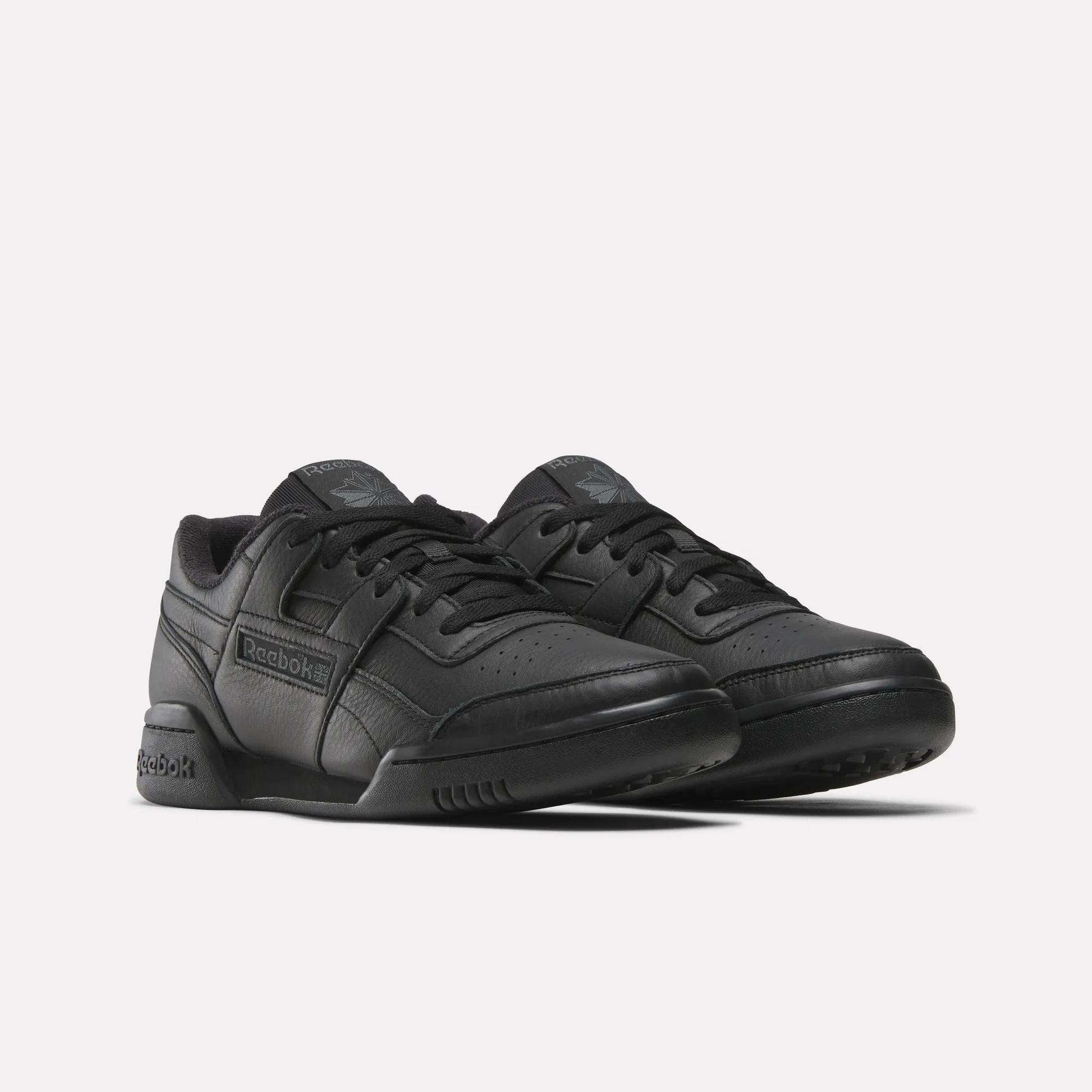 The Women's Workout Plus Shoes by Reebok feature a black low-top lace-up design with perforated toe detailing for a classic '80s fitness look, shown against a plain white background.