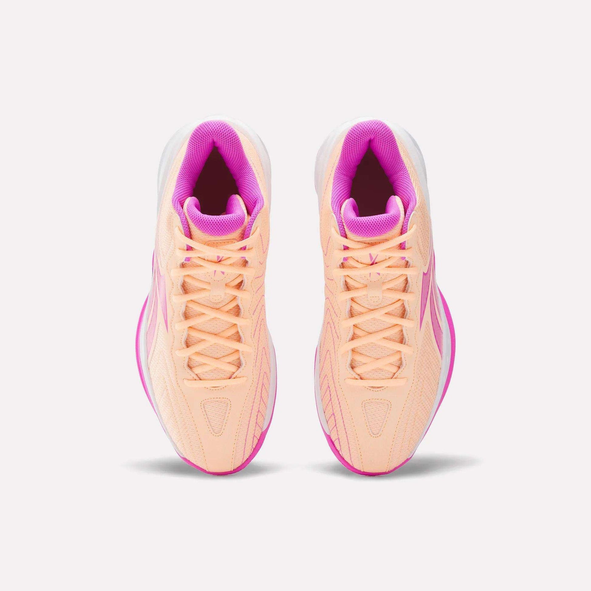 Top view of Reebok Press Basketball Shoes in peach with pink accents and white soles. Featuring EVA cushioning for comfort, these stylish and responsive shoes are side by side on a plain white background.