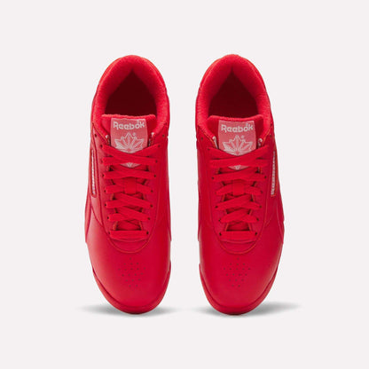 Top view of Reebok Women's Freestyle Lo Shoes in bright red with matching laces, a maple leaf logo on the tongue, and white branding, set on a plain white background—an eye-catching option for women.