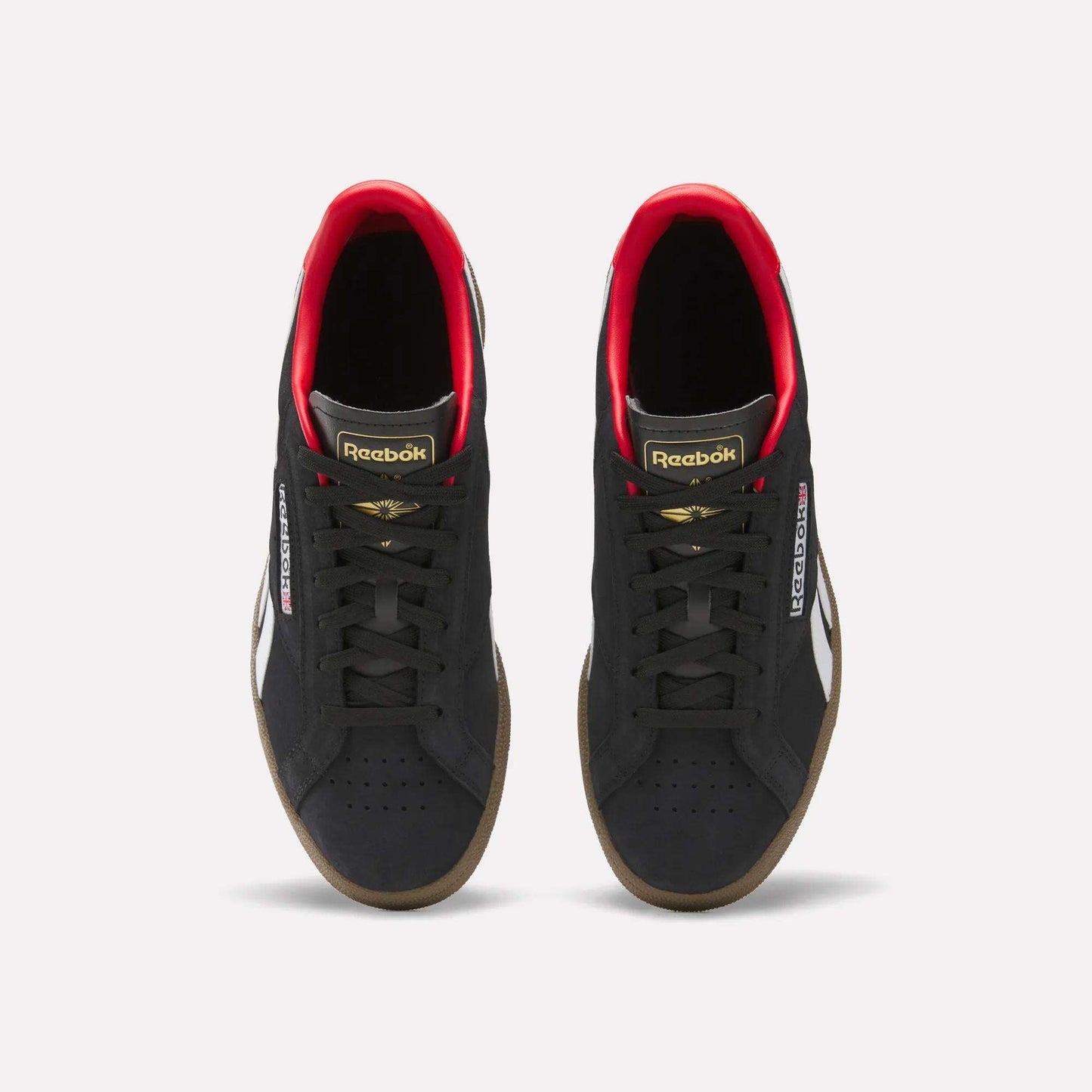 A pair of Reebok Club C Grounds UK Shoes in black with white side stripes, gold and red accents, black laces, and gum soles are shown from above on a white background—a perfect classic tennis-style casual shoe.