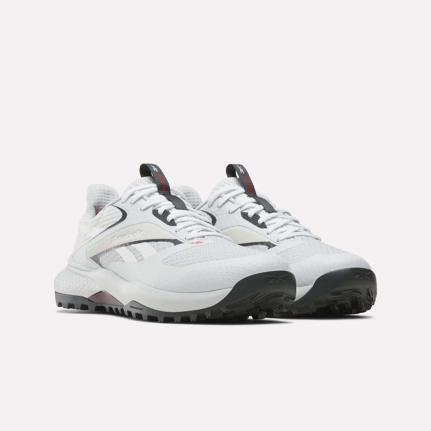 A pair of Reebok Nano Golf Shoes with a lightweight FlexWeave upper, thick textured soles, black and gray accents, and black pull tabs are placed side by side on a plain white background.