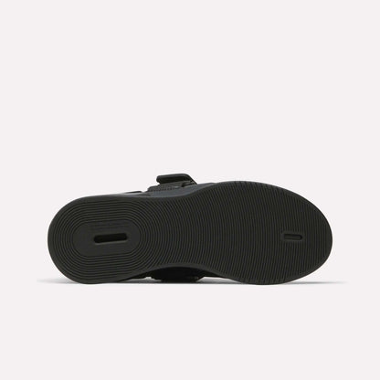 The image displays the black rubber sole of Reebok Women's Legacy Lifter IV Training Shoes, with a textured circular tread and a rectangular heel cut-out for support. The shoe is shown sole-up on a plain white background.