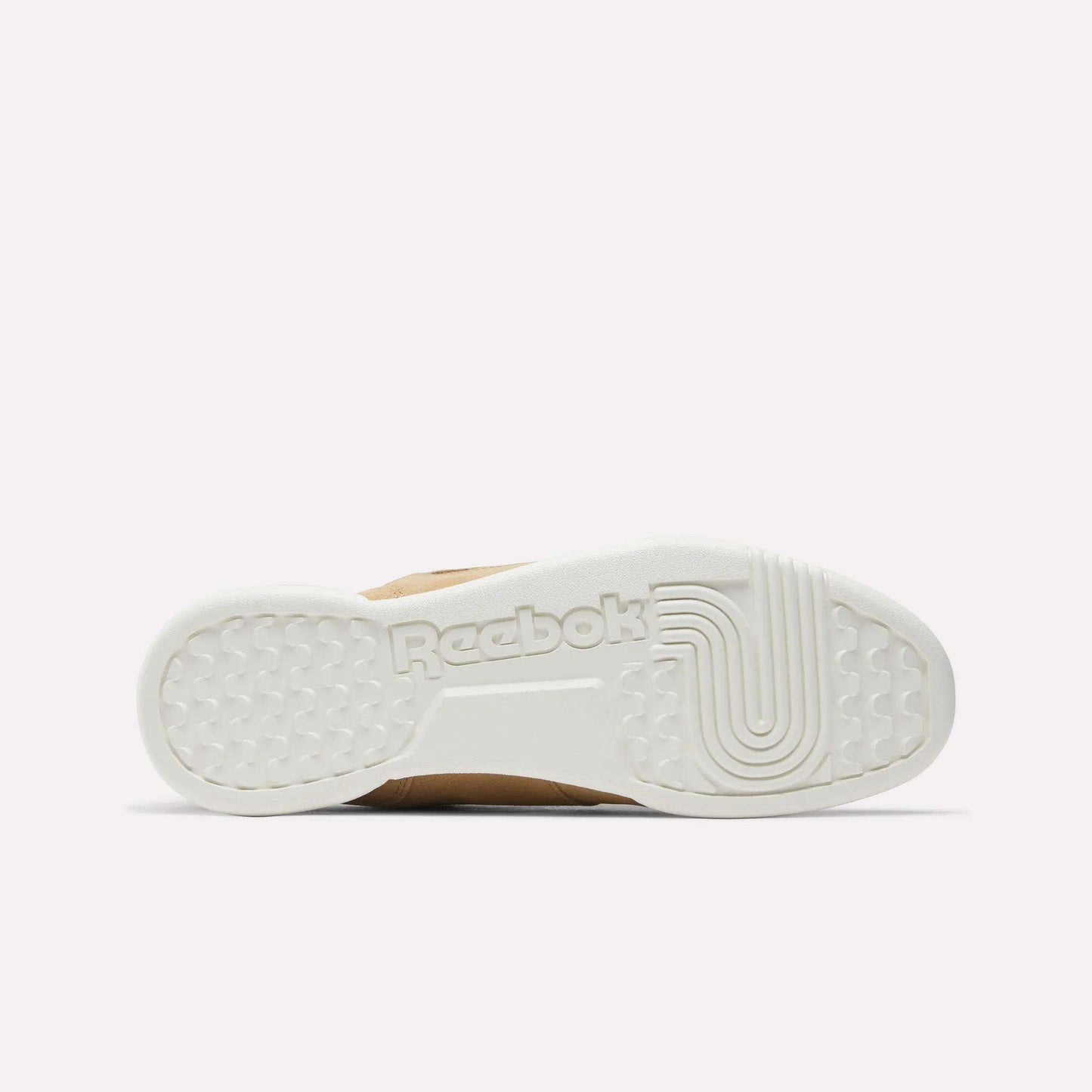The image shows the white rubber sole of Reebok Workout Plus Shoes from the bottom, featuring textured patterns and an embossed Reebok logo at the center. The plain light pink background evokes classic '80s fitness style.