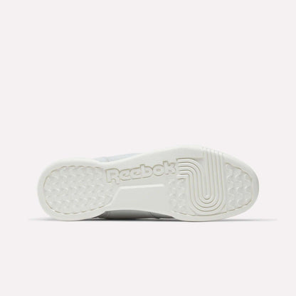 The image displays the sole’s bottom view of Reebok Workout Plus Shoes in white, featuring the Reebok logo and textured grip patterns for traction—a classic homage to '80s fitness style.