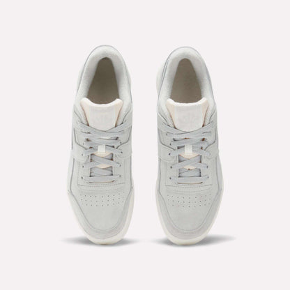 Top view of Reebok Workout Plus Shoes in light gray with white soles, laces, and subtle branding on the tongue. These classic sneakers channel authentic '80s fitness style and are shown side by side on a plain white background.