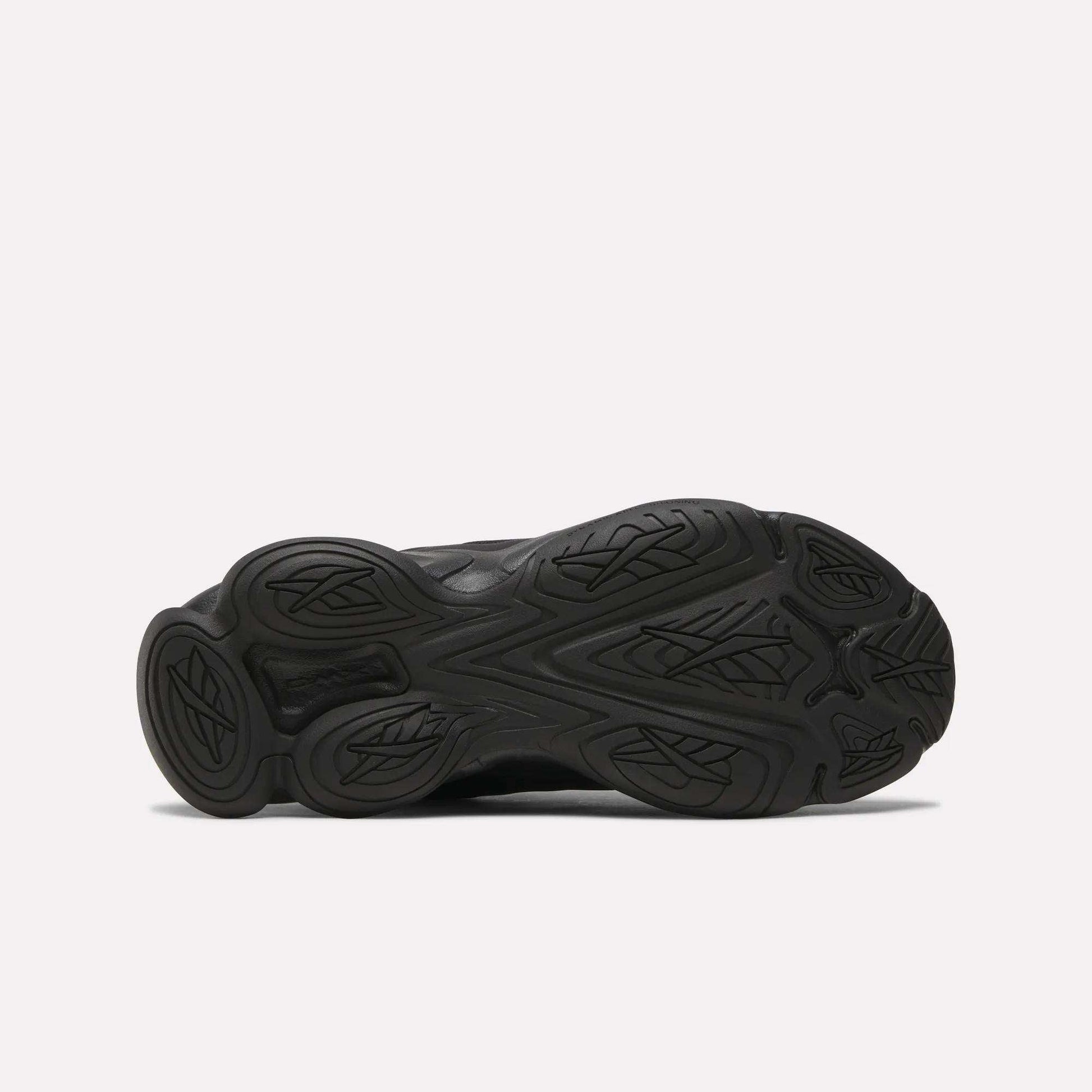 Bottom view of the Women's DMX Series 3000 Training Shoes by Reebok, showing a black textured rubber outsole with curved, leaf-like treads on a white background—ideal for walking and offering cushioned comfort.