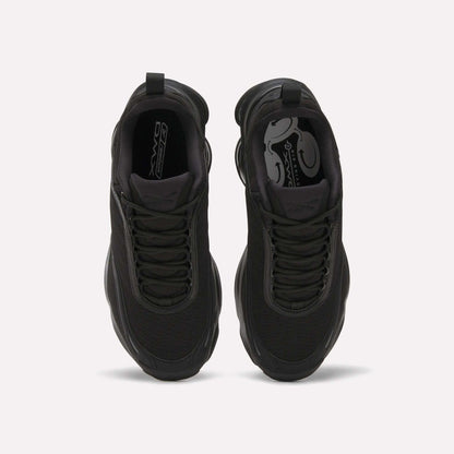A top-down view of a pair of Reebok Women's DMX Series 3000 Training Shoes in black with mesh uppers, black laces, a patterned black insole, and cushioned design, placed side by side on a light background.
