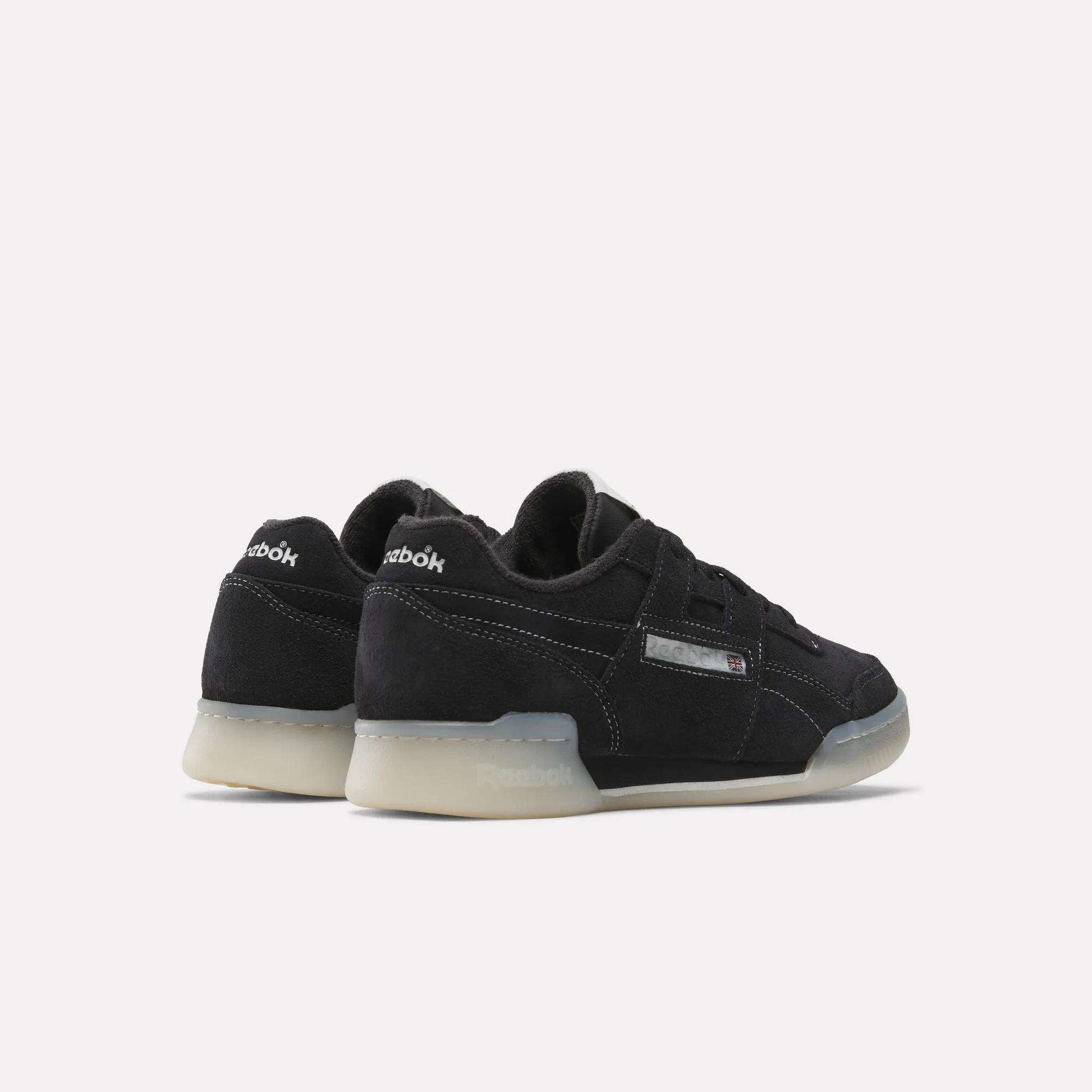 The Reebok Workout Plus Shoes feature a black suede finish, translucent rubber soles, and silver Reebok branding—reviving '80s fitness style on a clean white background.