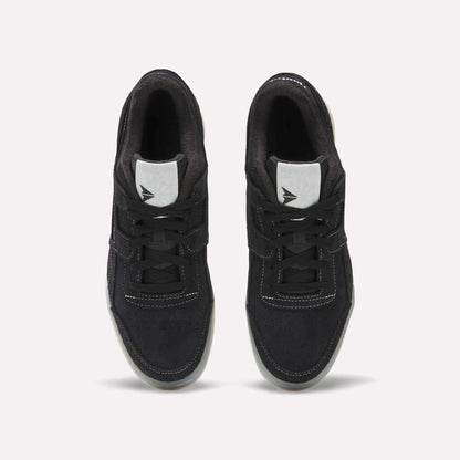 A pair of Reebok Workout Plus Shoes in black with white stitching and tongue labels, seen from above on a light background. The tied laces and side-by-side placement highlight their classic '80s-inspired fitness style.
