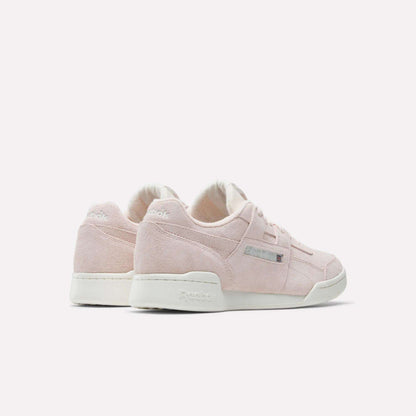 A pair of Reebok Workout Plus Shoes in light pink suede with white soles, displayed on a plain white background and angled to showcase the side and back views, highlighting their iconic '80s fitness style.