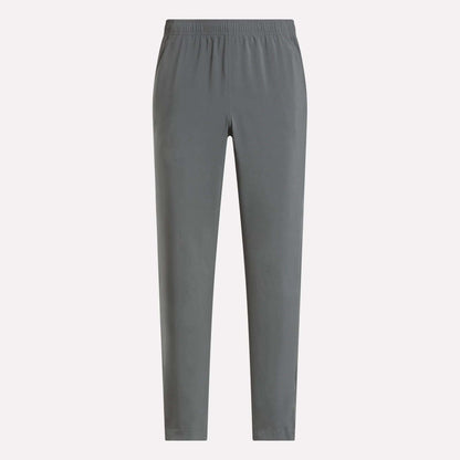 The Reebok Men's Train Woven Unlined Pants in plain gray feature an elastic waistband and are perfect as lightweight workout pants for the gym or everyday comfort, shown here against a light background.