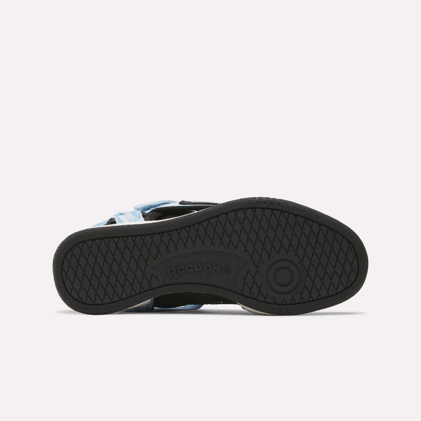 The image displays the black rubber sole of a Reebok x MARKET Club C 85 shoe, seen from below. Crisscross and circular tread patterns are present, with the Reebok logo at the center and part of the light blue upper in view.