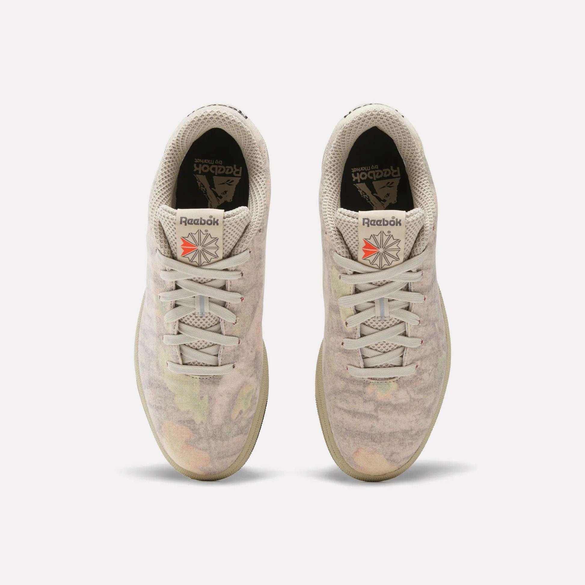 Top view of Reebok x MARKET Club C 85 Shoes in beige, featuring subtle pastel patterns, white laces, black insoles with the Reebok logo, and a red logo patch on each tongue. Court-inspired style with unique MARKET detailing.
