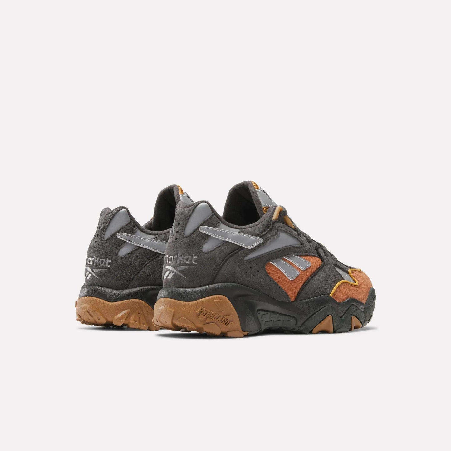 The Reebok x MARKET Preseason 94 Low Shoes feature chunky design, dark gray, brown, and mustard yellow accents with textured soles and branded heels—ideal dynamic trainers for your preseason collection.
