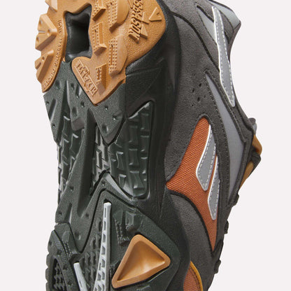 Close-up of the Reebok x MARKET Preseason 94 Low Shoes, featuring a rugged dark green, brown, and gum sole. Reflective and orange accents on the upper make these Reebok trainers ideal for any preseason collection.