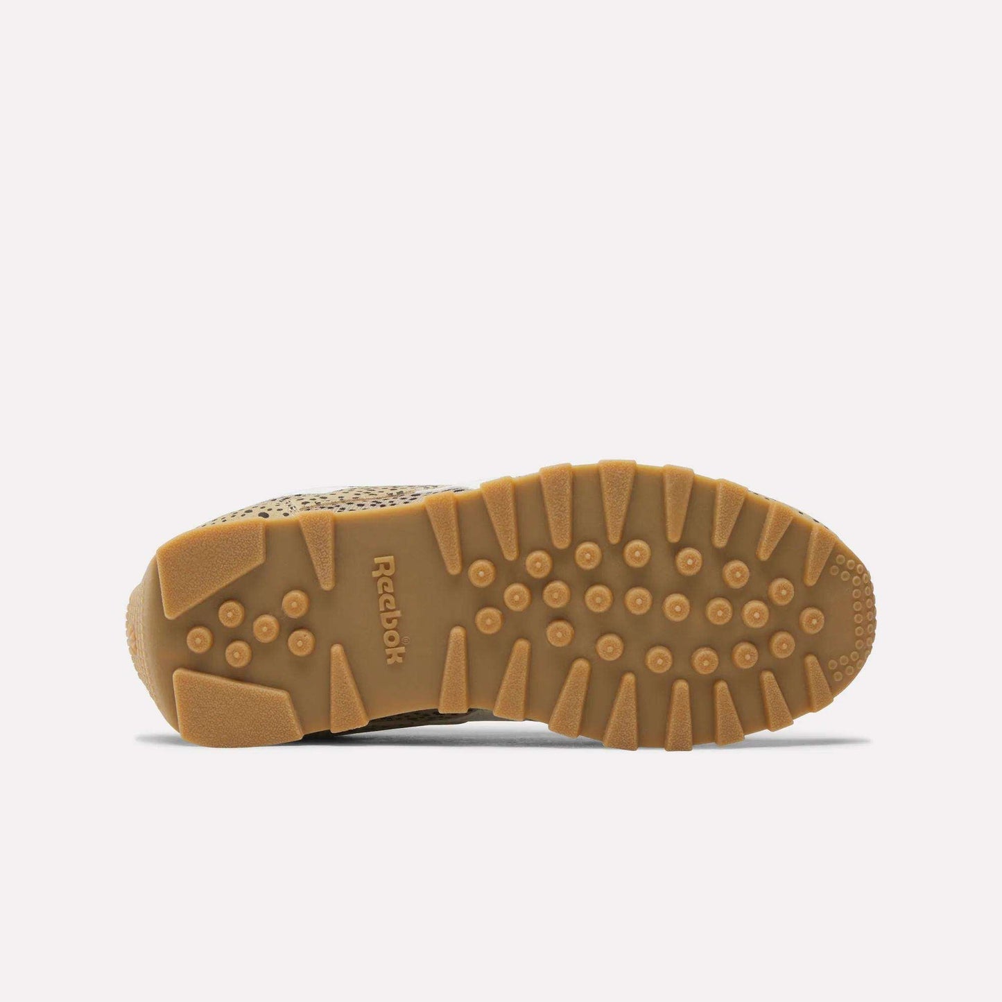 Bottom view of tan Reebok Classic AZ Shoes for big kids, these retro sneakers feature a textured gum sole with circular and rectangular treads for grip, shown against a plain white background.