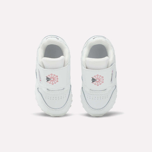 Kids' Classic Leather Shoes by Reebok for babies feature white leather, Velcro straps, a pink geometric star design, and small front text—ideal for everyday wear and shown on a plain light background.