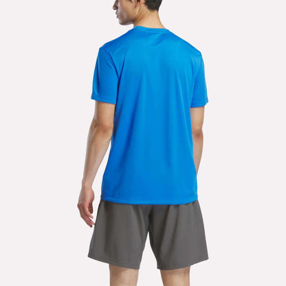 A person in a Men's Short Sleeve Tech Training T-Shirt by Reebok in bright blue and gray shorts stands with their back to the camera against a plain white background.