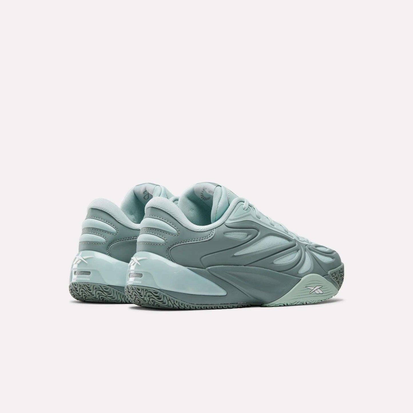 A pair of mint green Angel Reese 1 Basketball Shoes by Reebok with a sculpted, futuristic design and textured soles, featuring the Reebok Energy Return System, displayed on a white background from back and side angles.