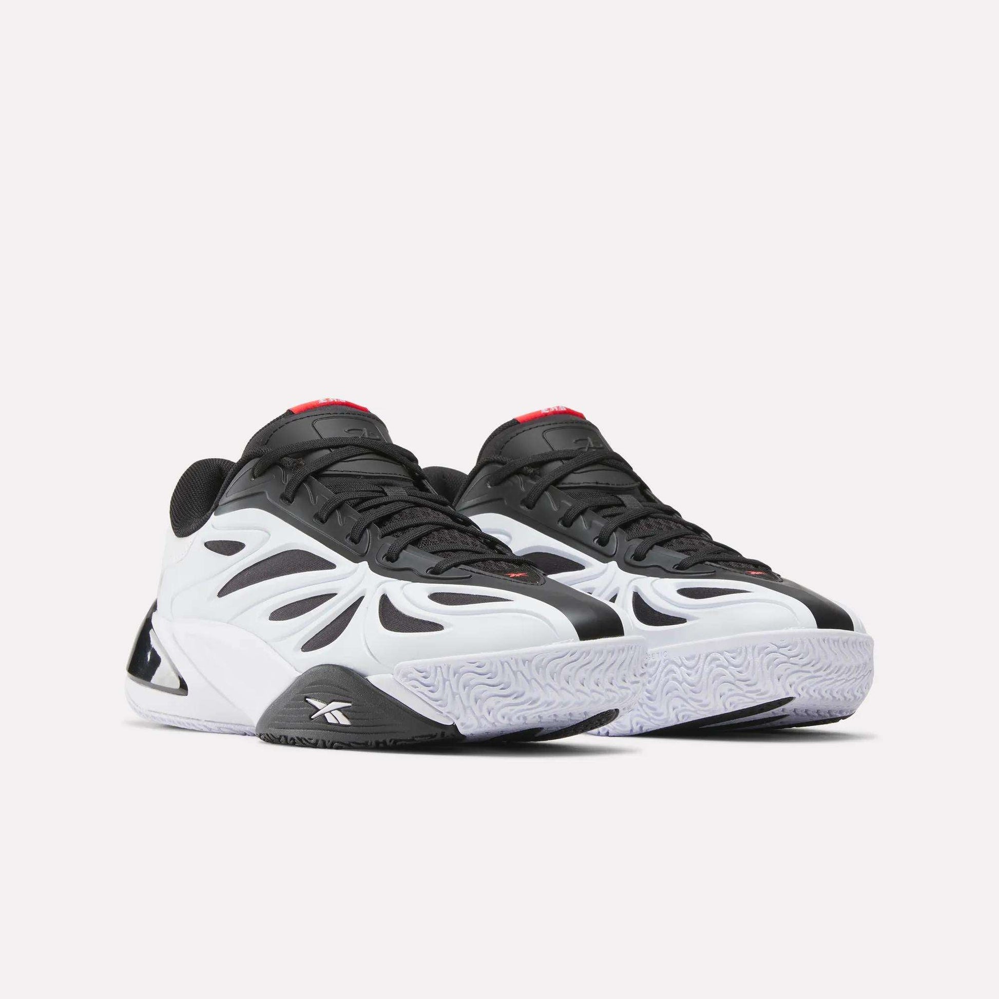 The Reebok Angel Reese 1 Basketball Shoes feature a wavy, futuristic black and white design with a chunky sole, red tongue accents, and Energy Return System for high performance. Shown on a white background.