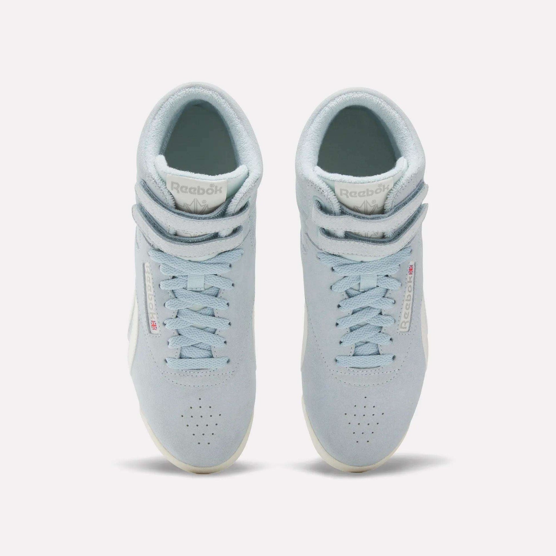 The Reebok Women's F/S Hi Shoes are light blue high top sneakers with suede uppers, white soles, perforated toes, and double Velcro straps at the top, shown from an overhead angle.
