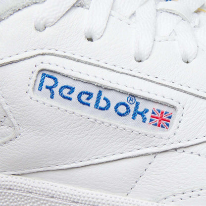 Close-up of the Men's Club C 85 Shoes by Reebok, a white leather sneaker with tennis inspiration, featuring a stitched blue Reebok logo and small Union Jack flag on the side.